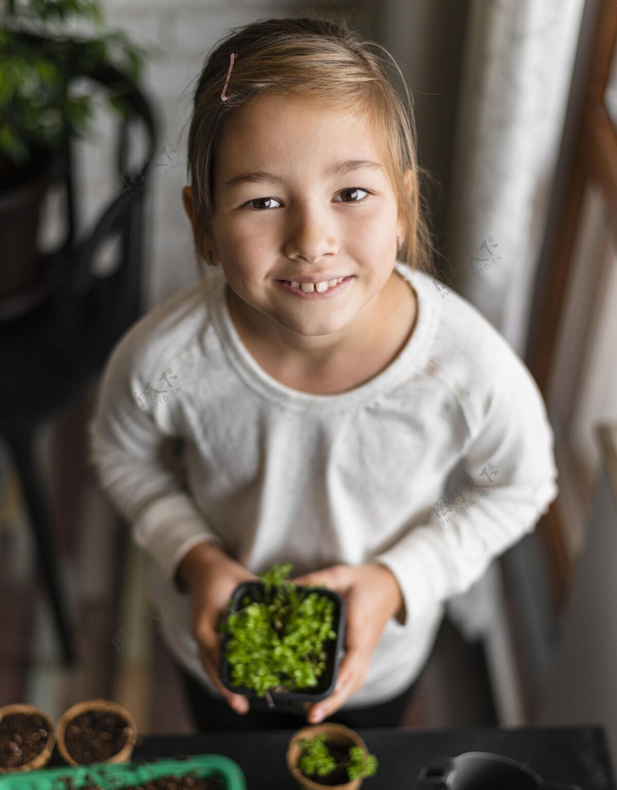 自然高角度的笑脸小女孩捧着花盆在家里农业孩子植物