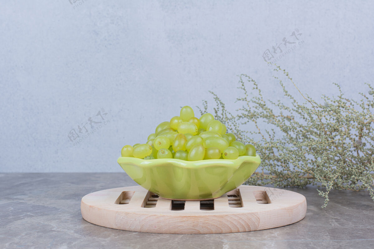 新鲜石桌上放着一碗绿葡萄葡萄自然水果