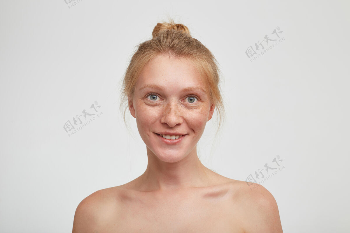 妈咪年轻的绿眼睛红发女性的画像 自然的妆容 看起来积极和微笑愉快 隔离在白墙与赤裸的肩膀特写发髻女士