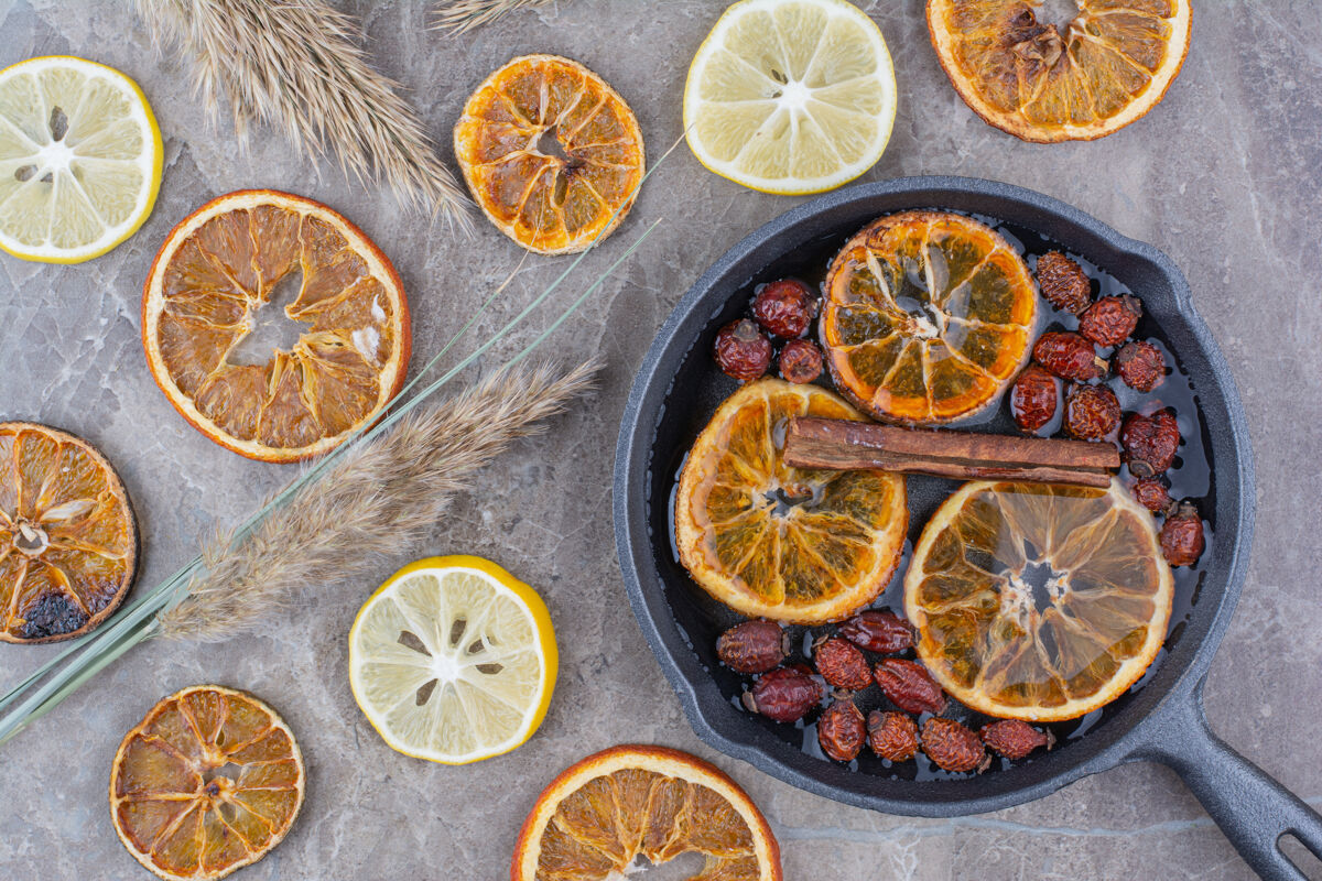 切片干橘子片 玫瑰果和肉桂放在黑锅上植物橙子水果