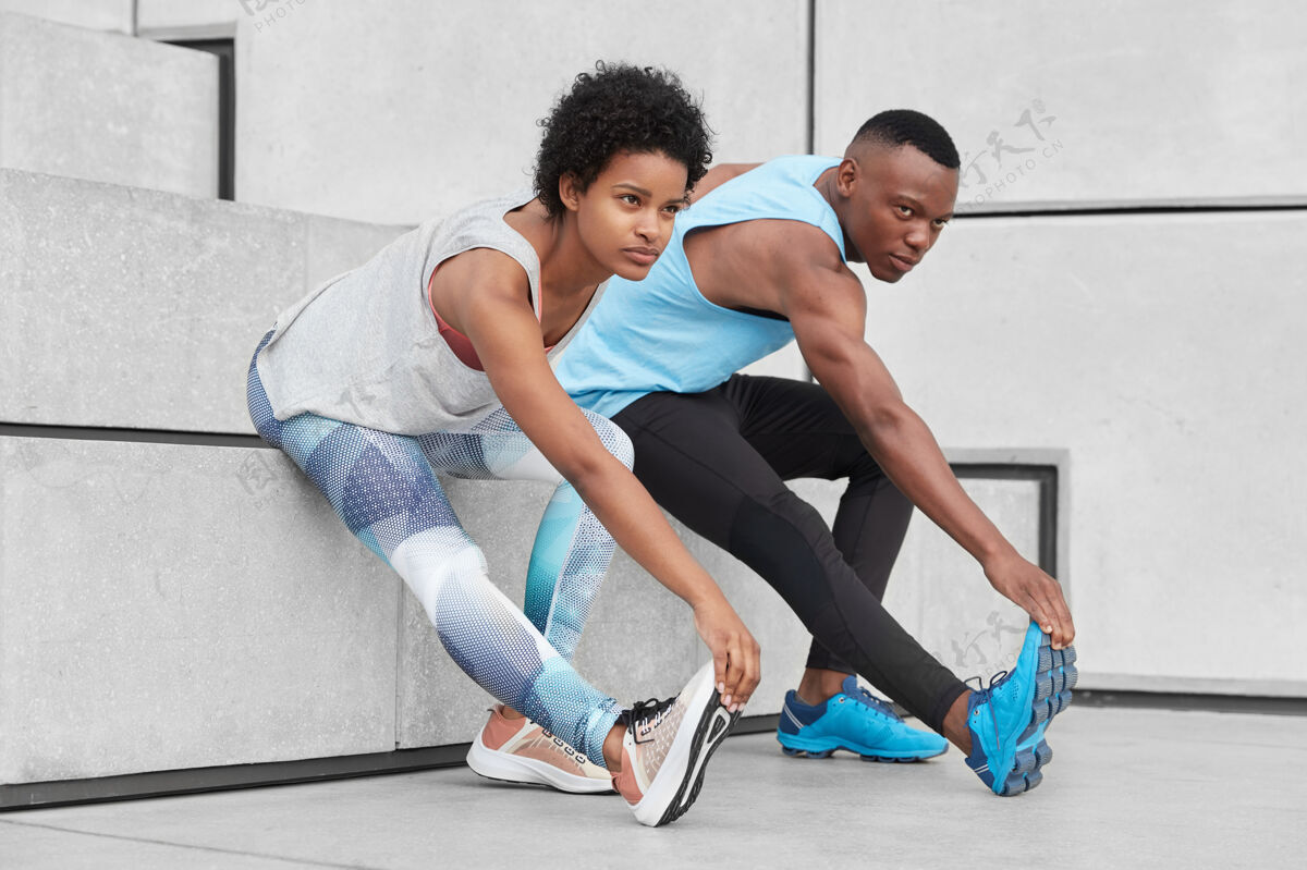 身体有动力的青少年表现出良好的柔韧性 脚部倾斜 在楼梯附近做伸展运动 穿着舒适的运动鞋进行训练 皮肤黝黑健康 肌肉强健的身体肌肉比赛姿势
