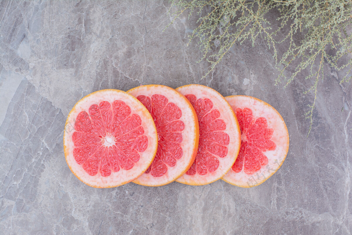 酸味柚子片放在石头上 背景是植物柑橘新鲜葡萄柚