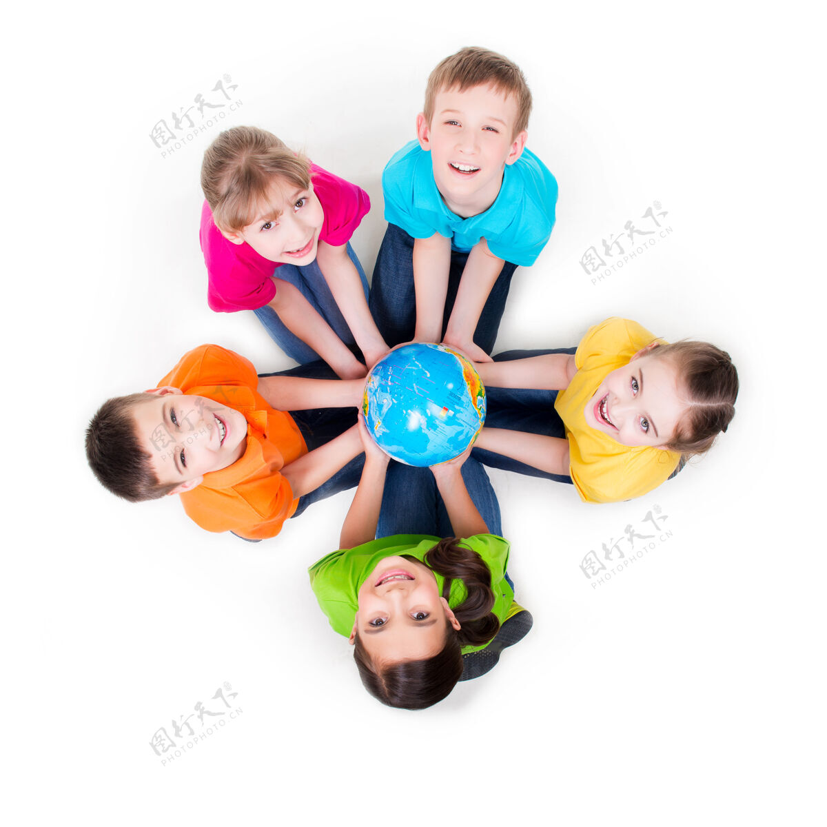 男孩一群微笑的孩子坐在地板上围成一个圈 手里拿着一个地球仪——孤立地站在白色地板上肖像年轻五