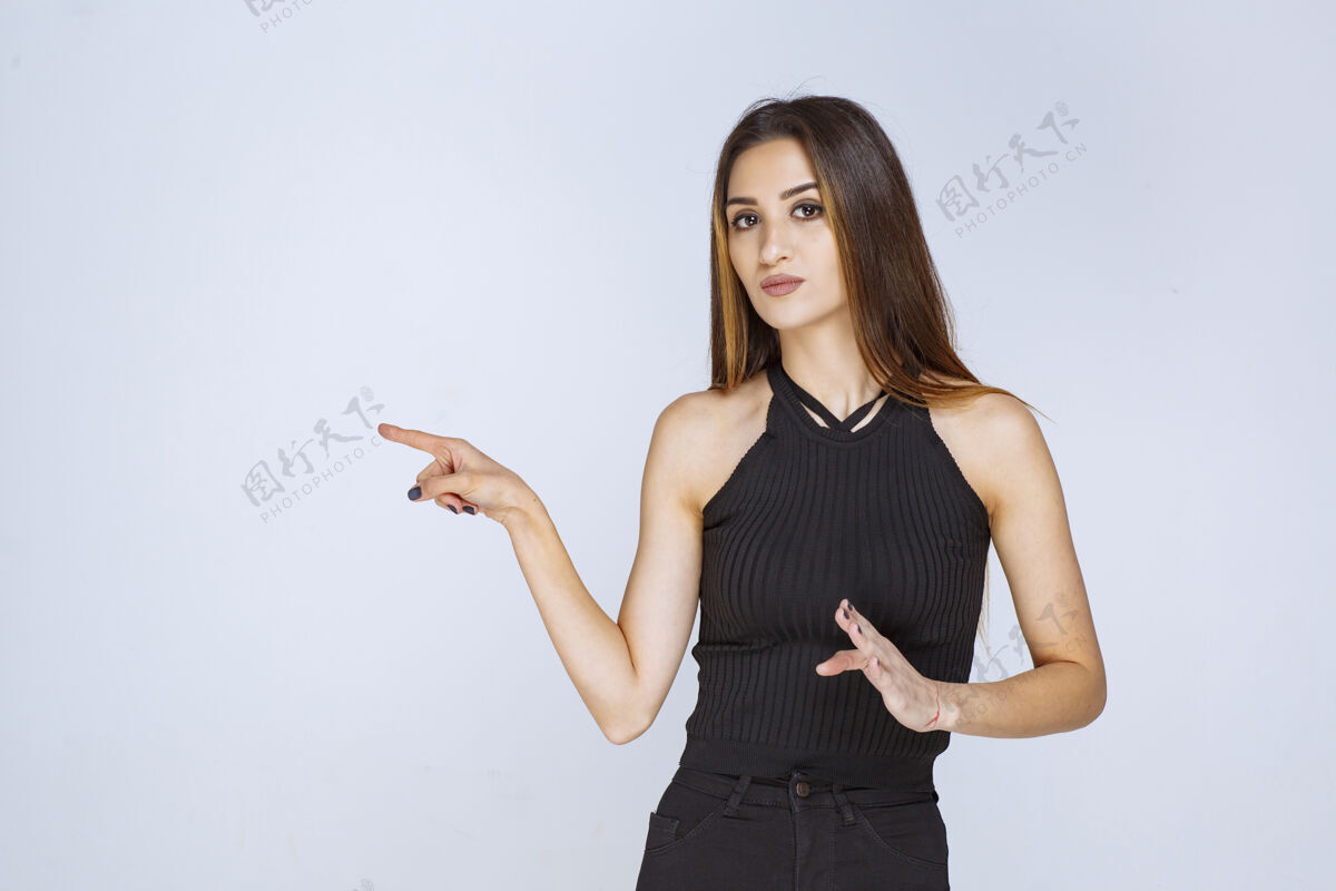 成人穿黑衬衫的女人用手指着某处方向年轻人物