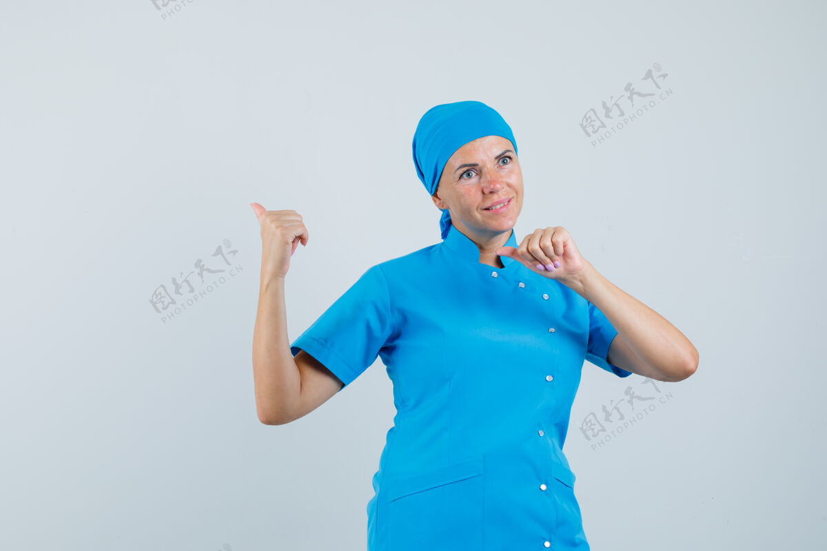 疾病穿着蓝色制服的女医生用大拇指指了指后面 看上去充满希望 正面视图肖像制服站立