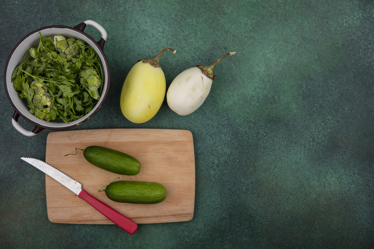 空间顶视图复制空间绿色在一个平底锅与黄瓜在一个菜板与刀和白色茄子绿色背景天空刀切割