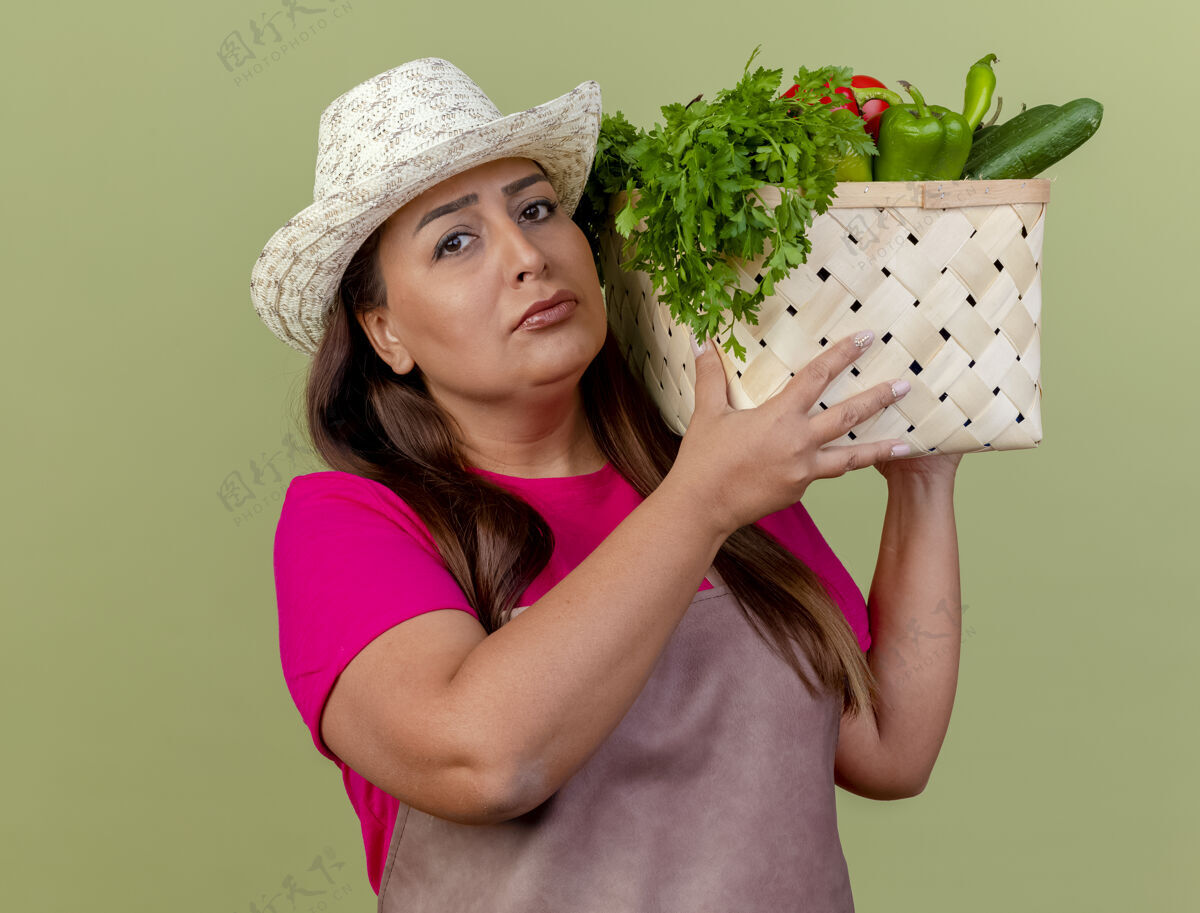 蔬菜围裙戴帽子的中年园丁妇女拿着装满蔬菜的板条箱女人板条箱帽子