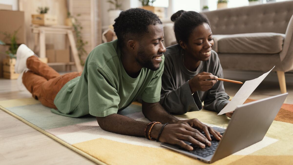 战略笑脸夫妇在地板上正计划用笔记本电脑重新装修房子家庭夫妇笔记本电脑