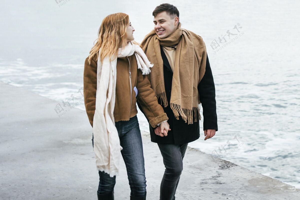 水平冬天 一对情侣手牵着手在海滩边散步女人业余爱好冬天