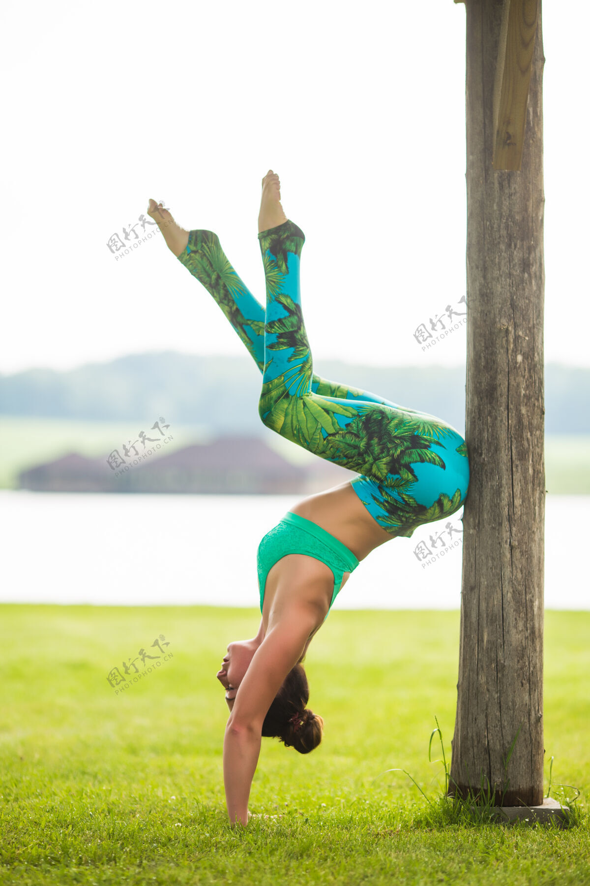 女人可爱的年轻女子在绿色公园做倒立练习女性健身瑜伽