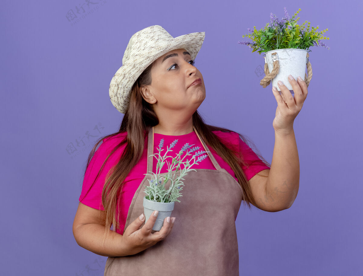 植物围裙戴帽子捧着盆栽的中年园丁花园女人围裙