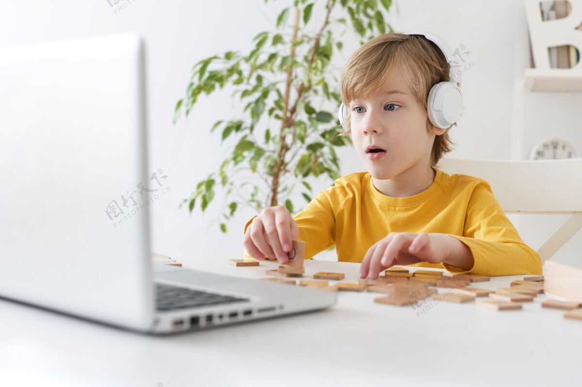 笔记本电脑好奇的小男孩在家里用笔记本电脑和耳机年轻科技业余爱好