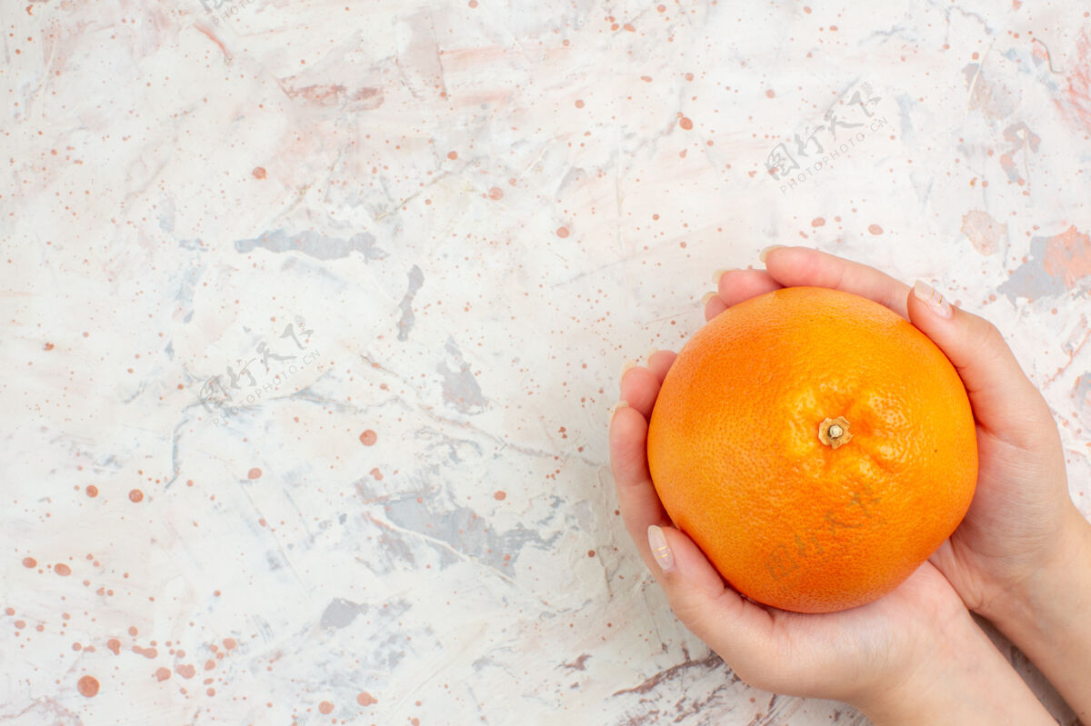 柑橘顶视图新鲜的橙色在女性手上明亮孤立的表面自由空间维生素顶级果汁