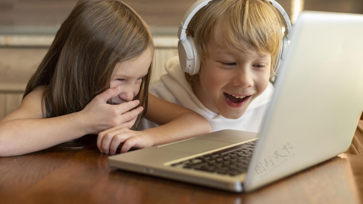 娱乐微笑的孩子一起使用笔记本电脑和耳机笔记本电脑设备电子