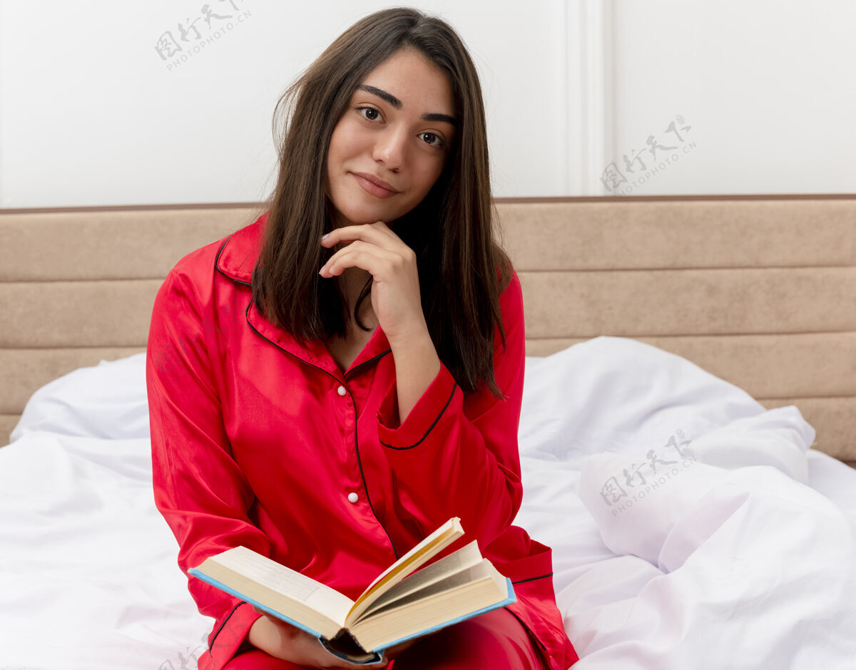 床穿着红色睡衣在床上放松的年轻美女书卧室睡衣