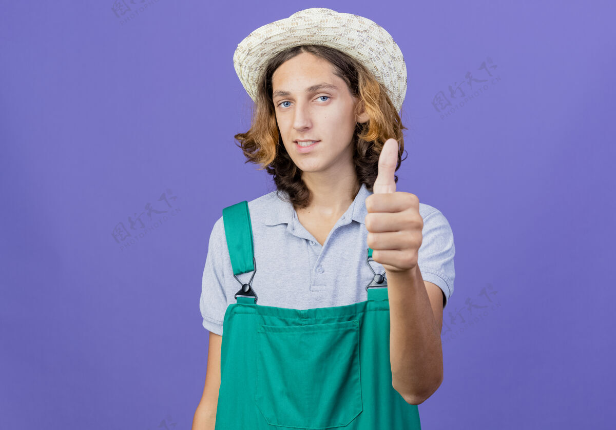 向上穿连体衣戴帽子的年轻园丁拇指微笑帽子