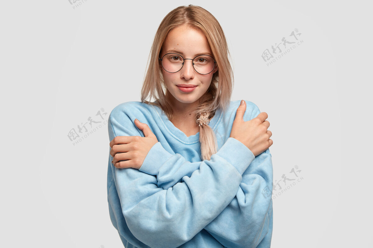 眼镜迷人美丽的年轻白人女性穿着超大号浅蓝色毛衣情绪照片放松