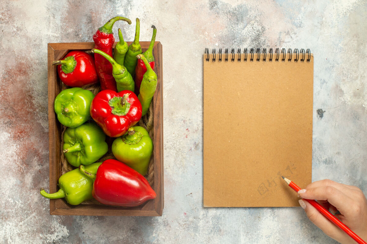 顶部顶视图红色和绿色的辣椒辣椒在木箱笔记本红色铅笔在女性手裸体表面番茄胡椒蔬菜
