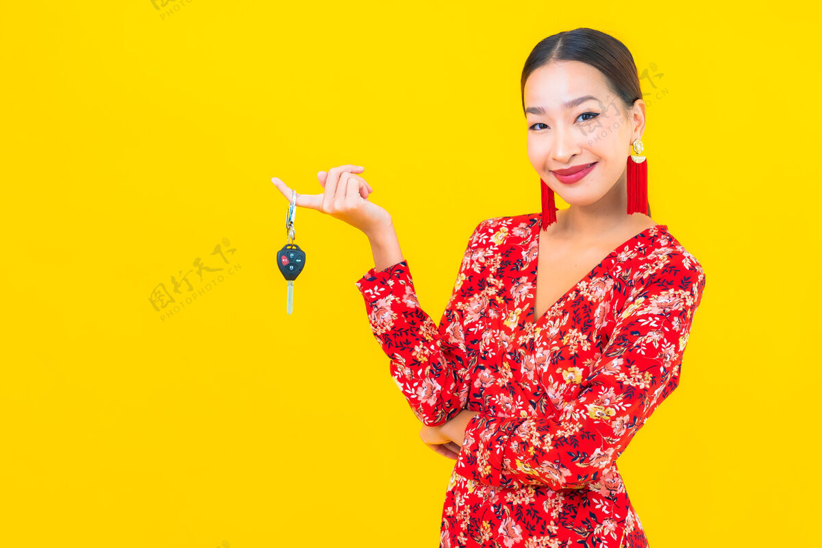坐着在黄色的墙上画一幅美丽的亚洲年轻女子拿着车钥匙亚洲人成人汽车