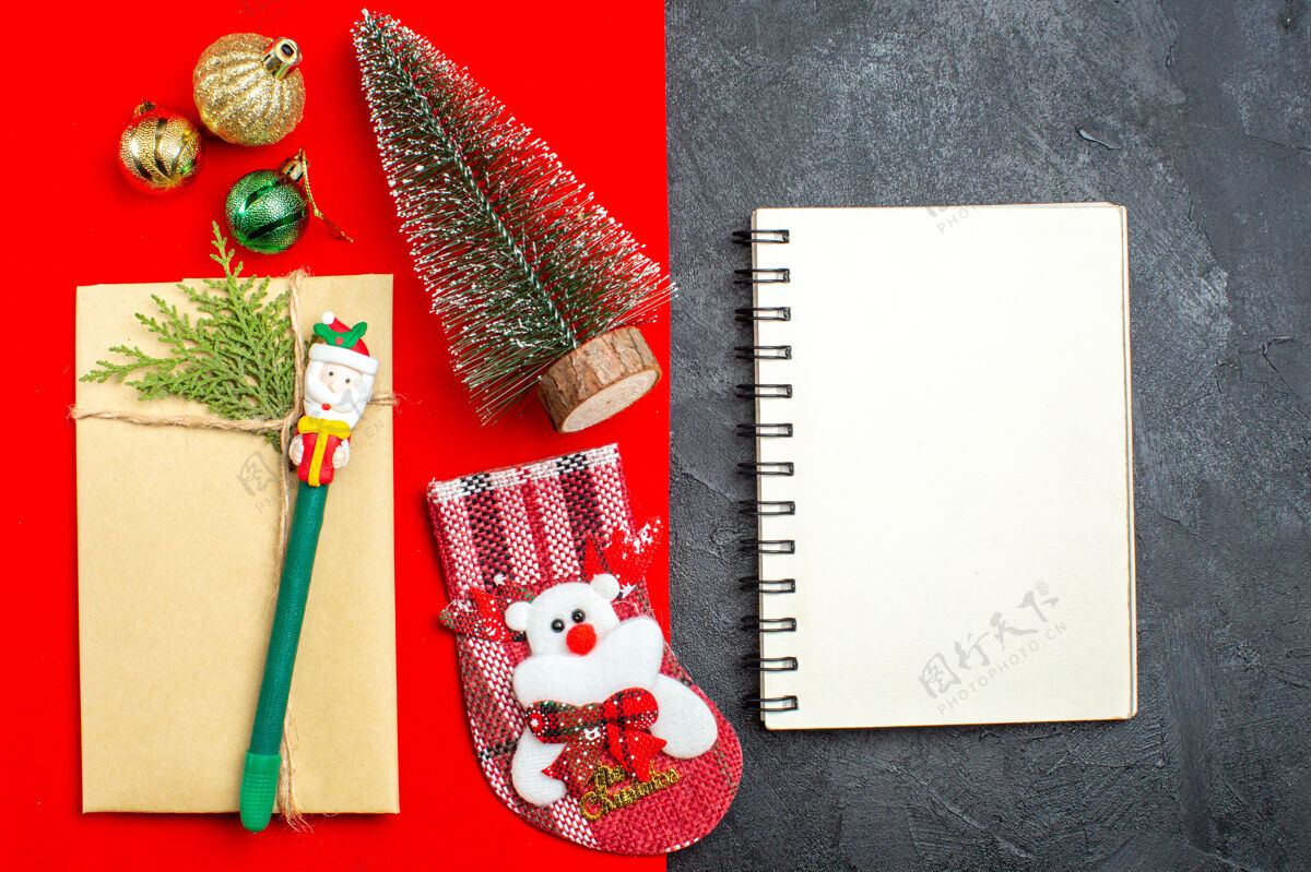 现金xsmas心情俯瞰图 红色和黑色背景上的笔记本旁边有圣诞树装饰配件礼品袜子铅笔盒钱开销