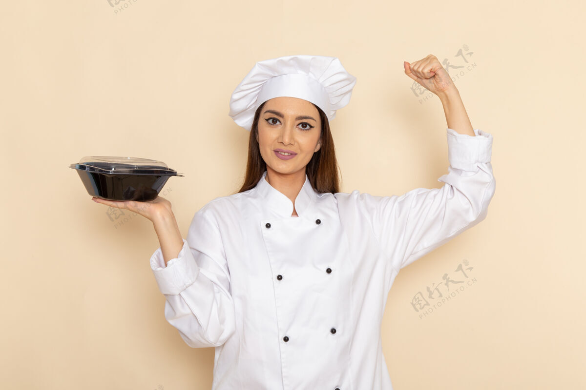 人身穿白色厨师服的年轻女厨师手持平底锅 在白色墙壁上活动工作专业烹饪