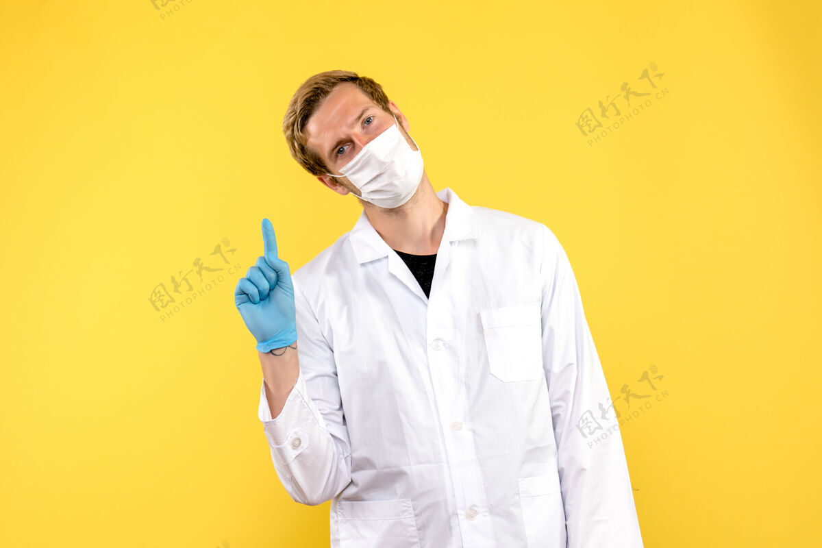 实验室外套正面图黄色背景上戴着面罩的男医生-医疗大流行外套医院专业人员