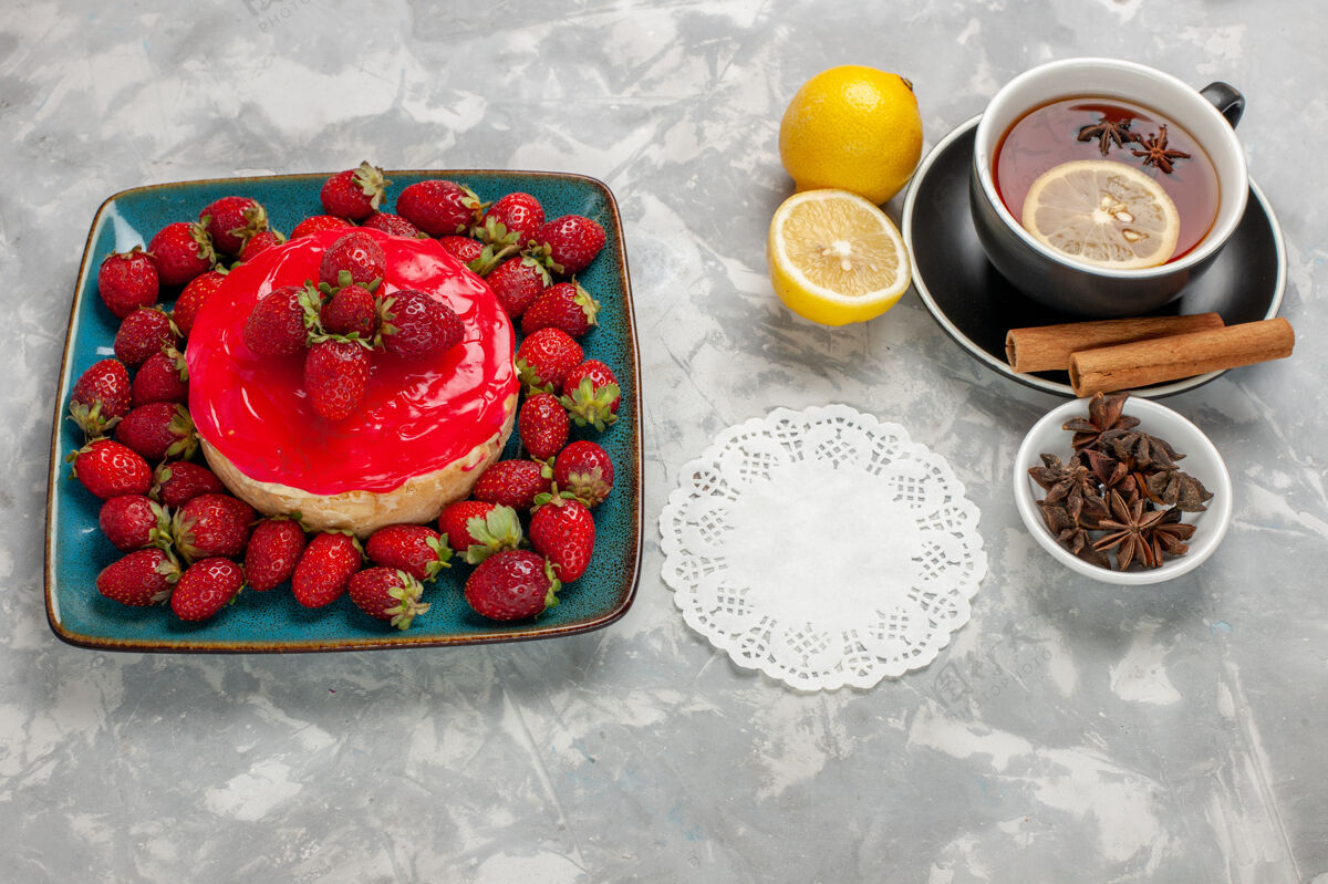 草莓正面图美味的蛋糕小馅饼 白色表面有一杯茶和新鲜草莓生的甜食前面