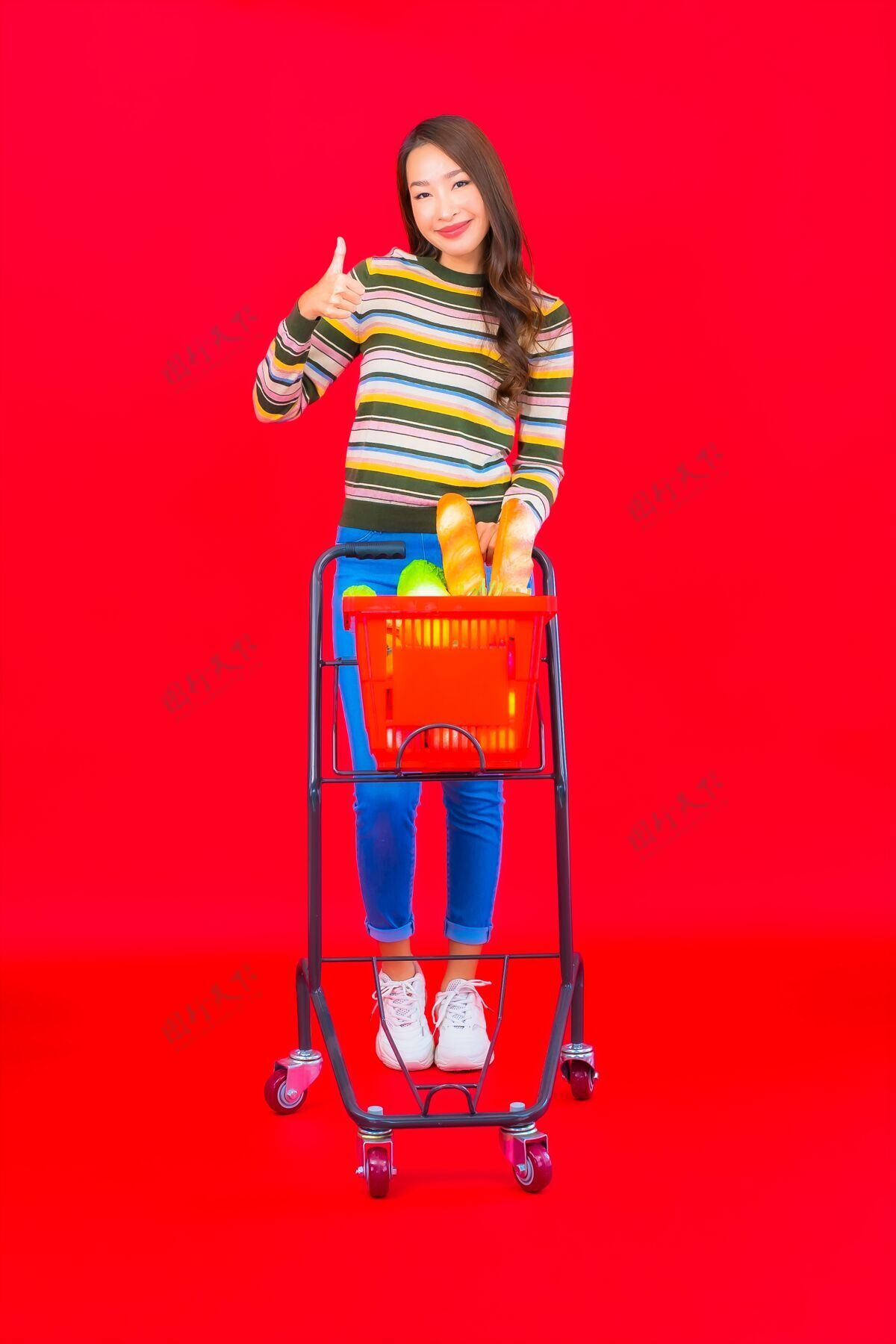 女士在红色的隔离墙上 一位美丽的亚洲年轻女子拿着超市的购物篮杂货店有机顾客
