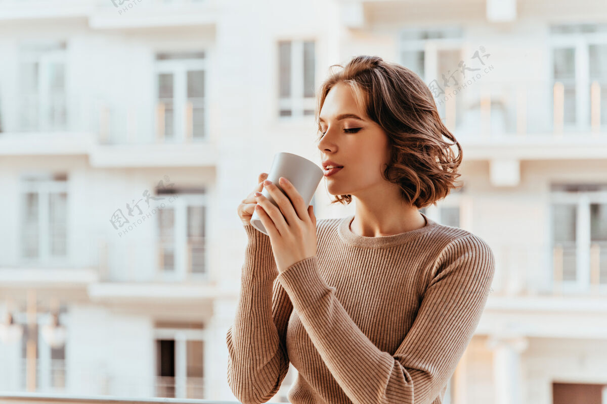 休闲灵感来源于一位留着卷发的白人女士喝茶美丽的年轻女子在寒冷的秋日早晨享受着咖啡风景快乐卷发