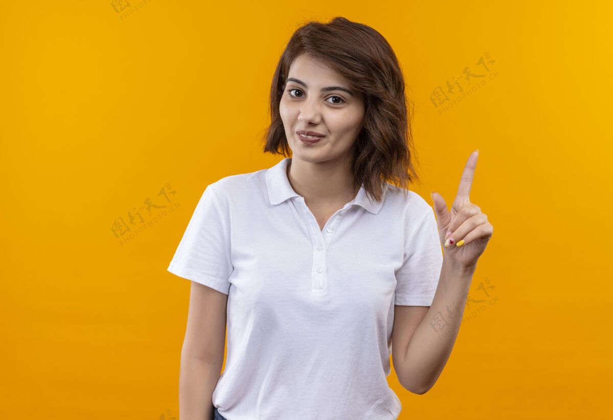 年轻一个短发女孩穿着白色马球衫 微笑着 自信地用手指着自信马球衬衫