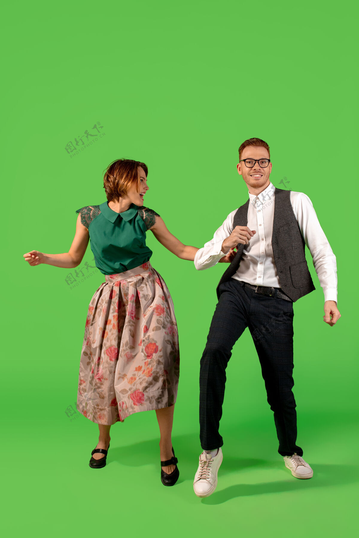 礼服摇滚乐老式的年轻女子在绿色工作室背景下孤立地跳舞年轻时尚的男人和女人情侣两个男人