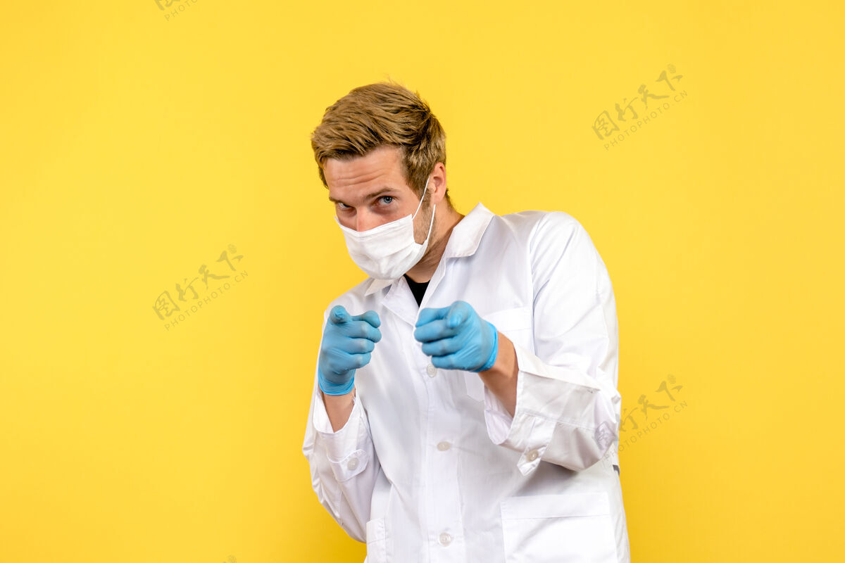 微笑正面图男性医生指着黄色背景卫生医疗大流行病毒实验室医疗成人