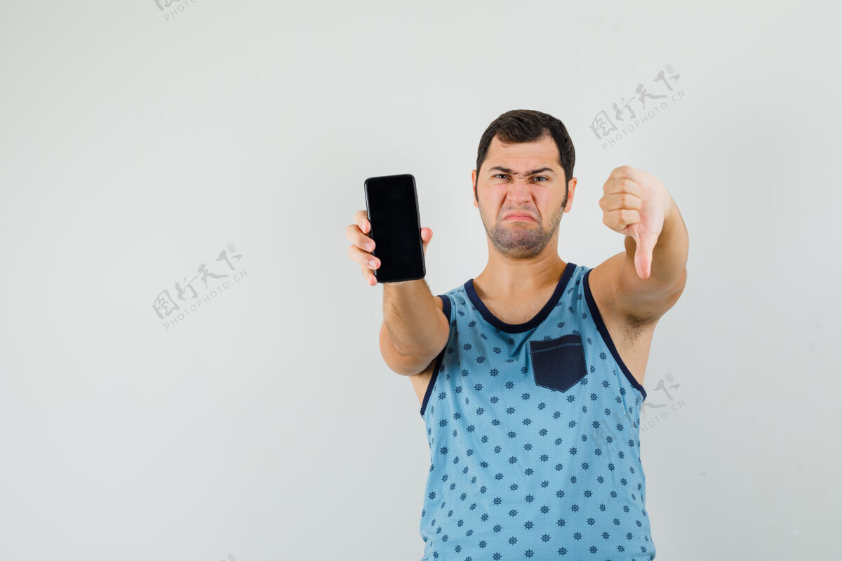 男一个拿着手机的年轻人 穿着蓝色的单品 大拇指朝下 看上去很不满意成功秀放下