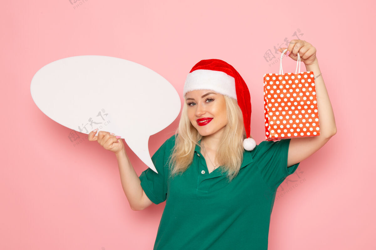 成人正面图年轻女子手持白色大招牌 在粉色墙上呈现照片雪色新年度假女人女人雪颜色