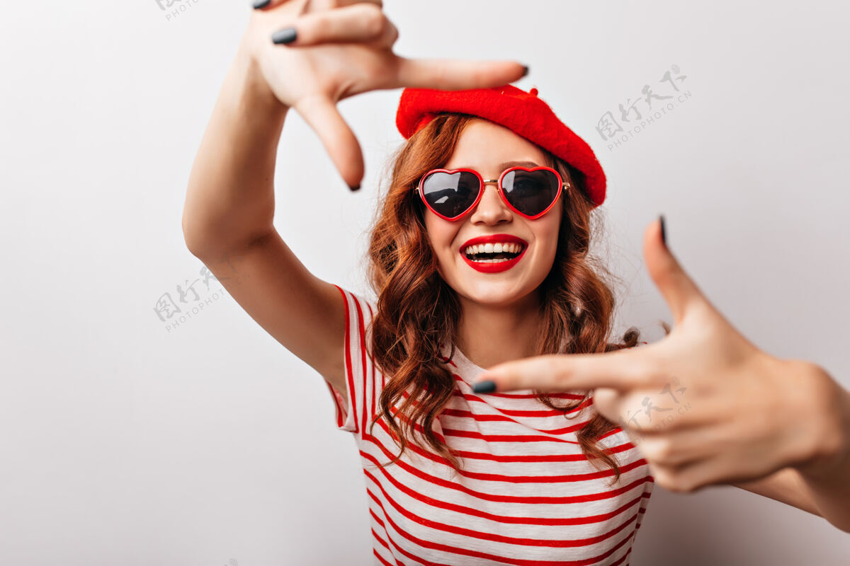 Swoosh穿着红色贝雷帽的美丽的欧洲女人表达着幸福戴着墨镜的卷发女孩兴奋地笑着休闲正面法国