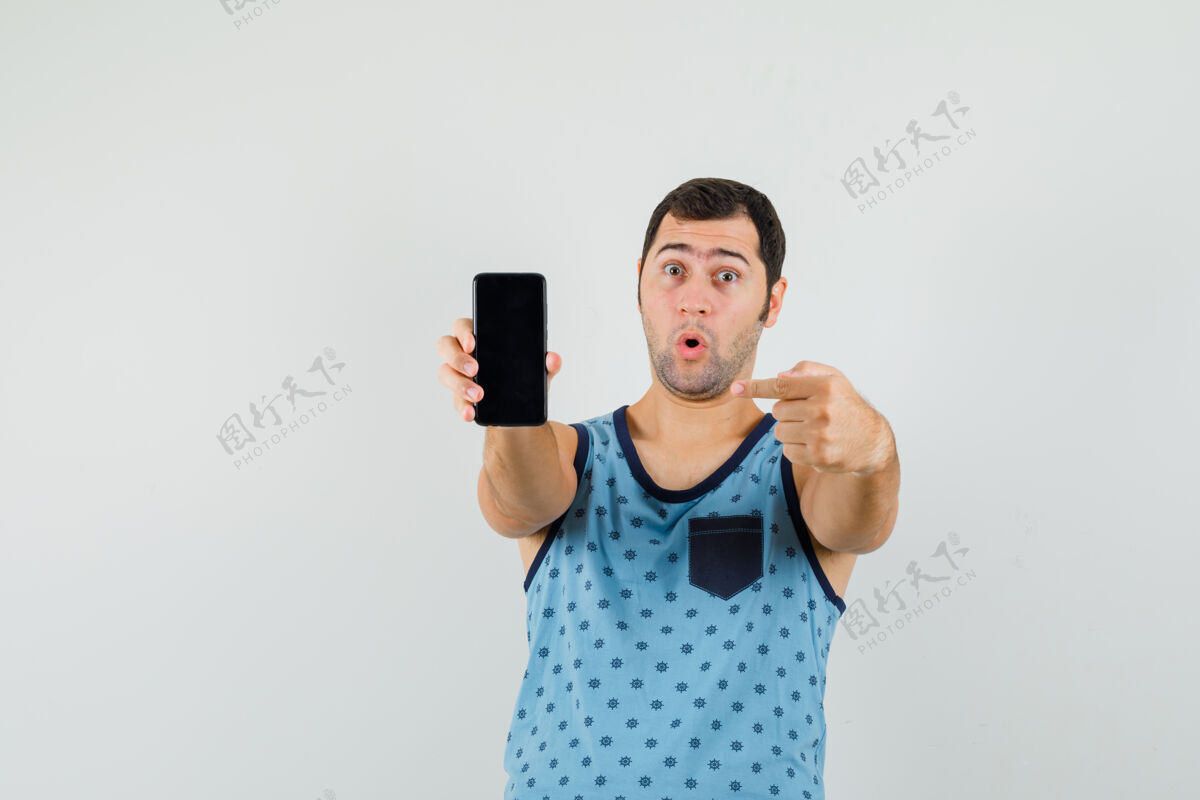 衬衫年轻人指着手机在蓝色单品和期待惊讶休闲男惊喜
