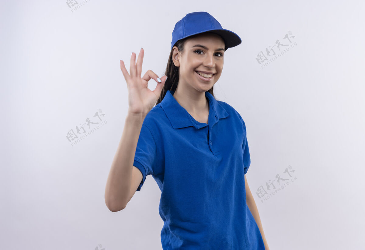 女孩身着蓝色制服 头戴鸭舌帽的年轻送货员微笑着自信地展示着ok标志微笑显示交付