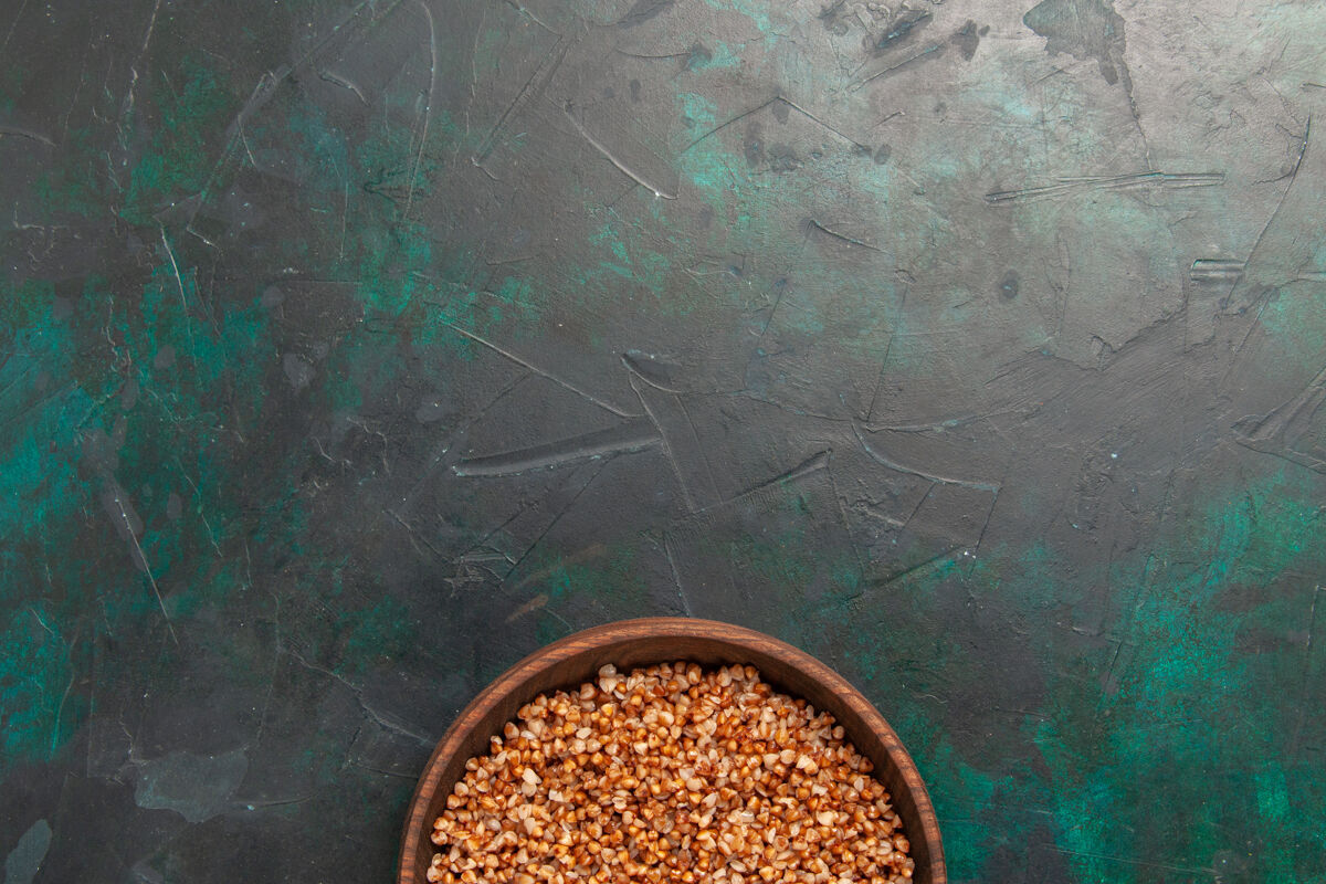生的顶视图熟荞麦美味的饭菜内棕色盘子在深绿色的表面产品顶盘子