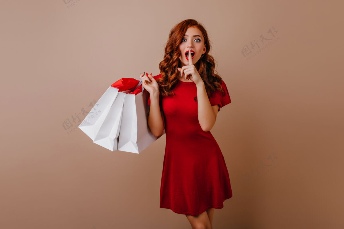 漂亮奇妙的欧洲女孩在购物后带着惊奇的微笑摆姿势快乐的姜女士拿着购物袋折扣快乐姜黄色