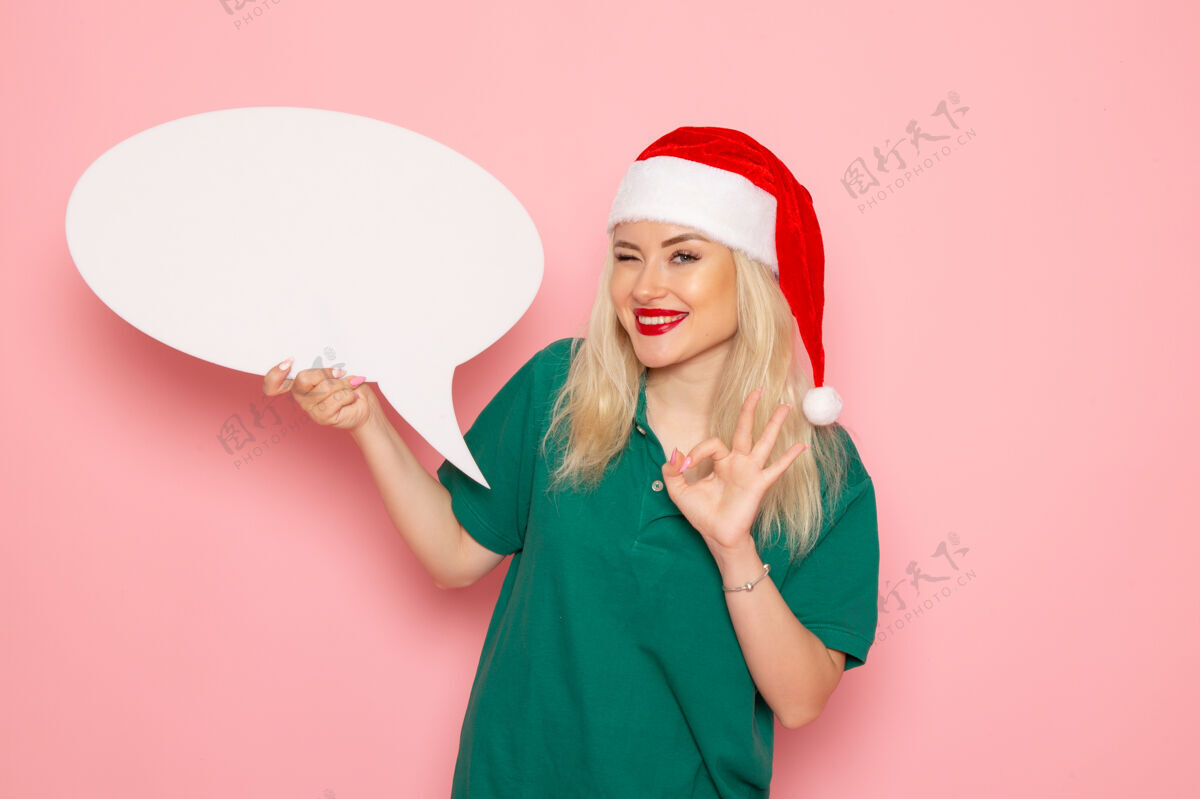 大正面图年轻女子手持白色大招牌在粉色墙上女士赠送雪彩照片新年假期圣诞节风景女人