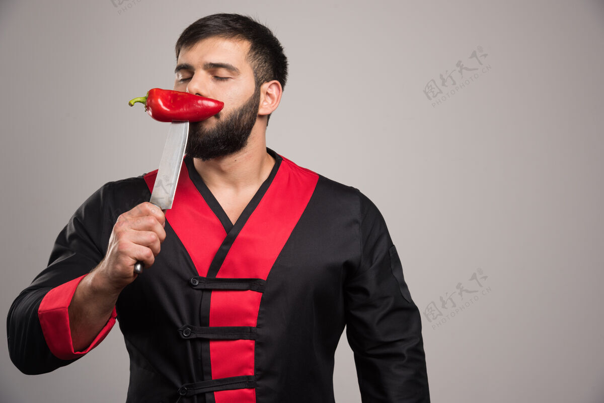 吃闭着眼睛的男人嗅着刀上的红辣椒人表情胡椒