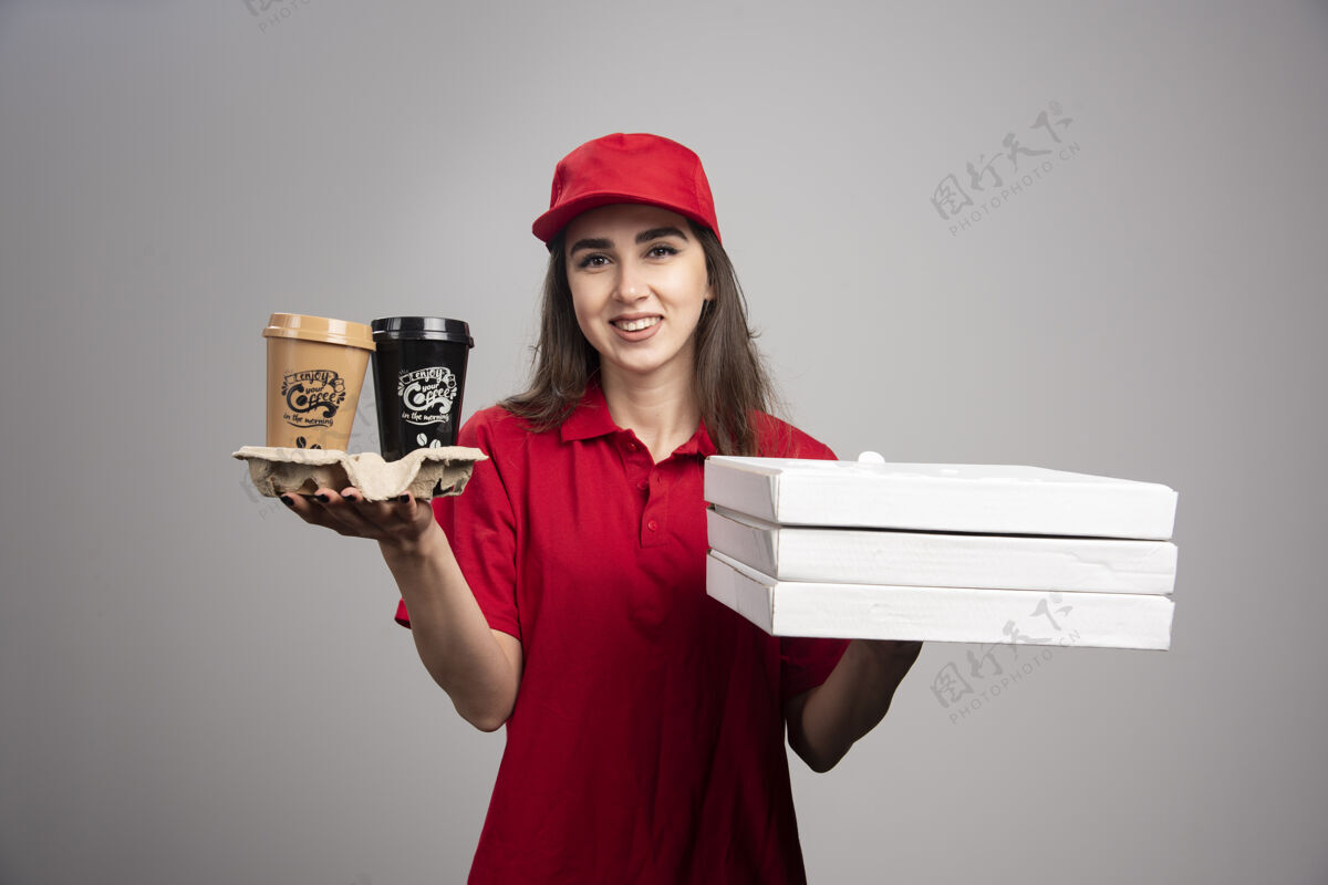女孩送披萨和咖啡杯的女人站在灰色的墙上工作披萨饮料