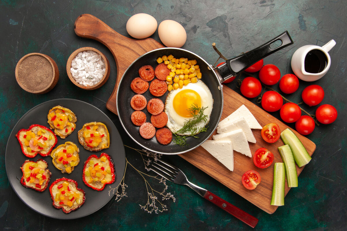 晚餐顶视图炒鸡蛋与切片香肠新鲜西红柿和生鸡蛋在黑暗的背景早餐香肠西红柿