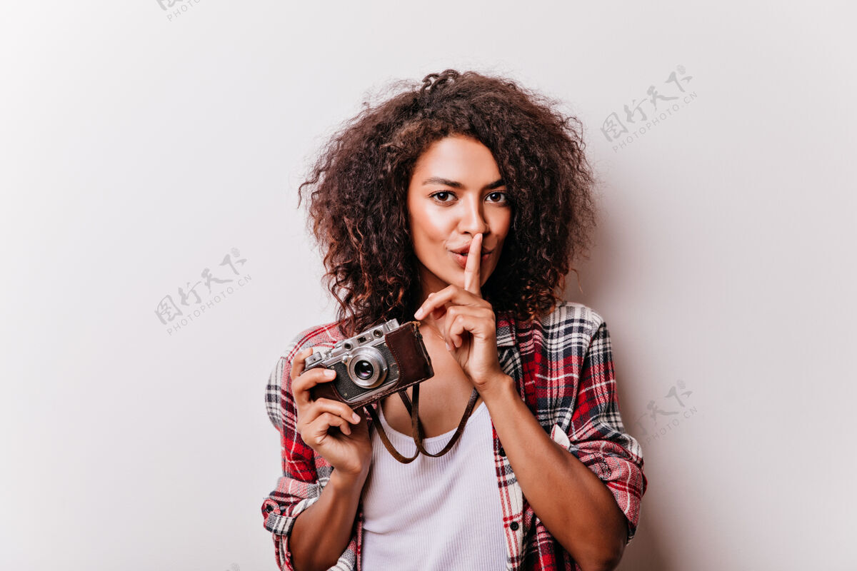 卷发幽默的年轻女士带着相机微笑着站着优雅的黑人女孩在拍照时尚寒冷波浪发