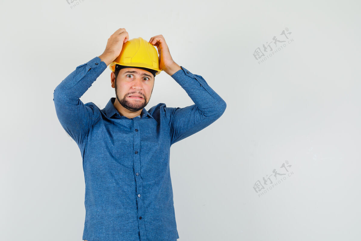 头脑风暴年轻的工人手挽着头 穿着衬衫 戴着头盔 看上去很无助工人沟通团结