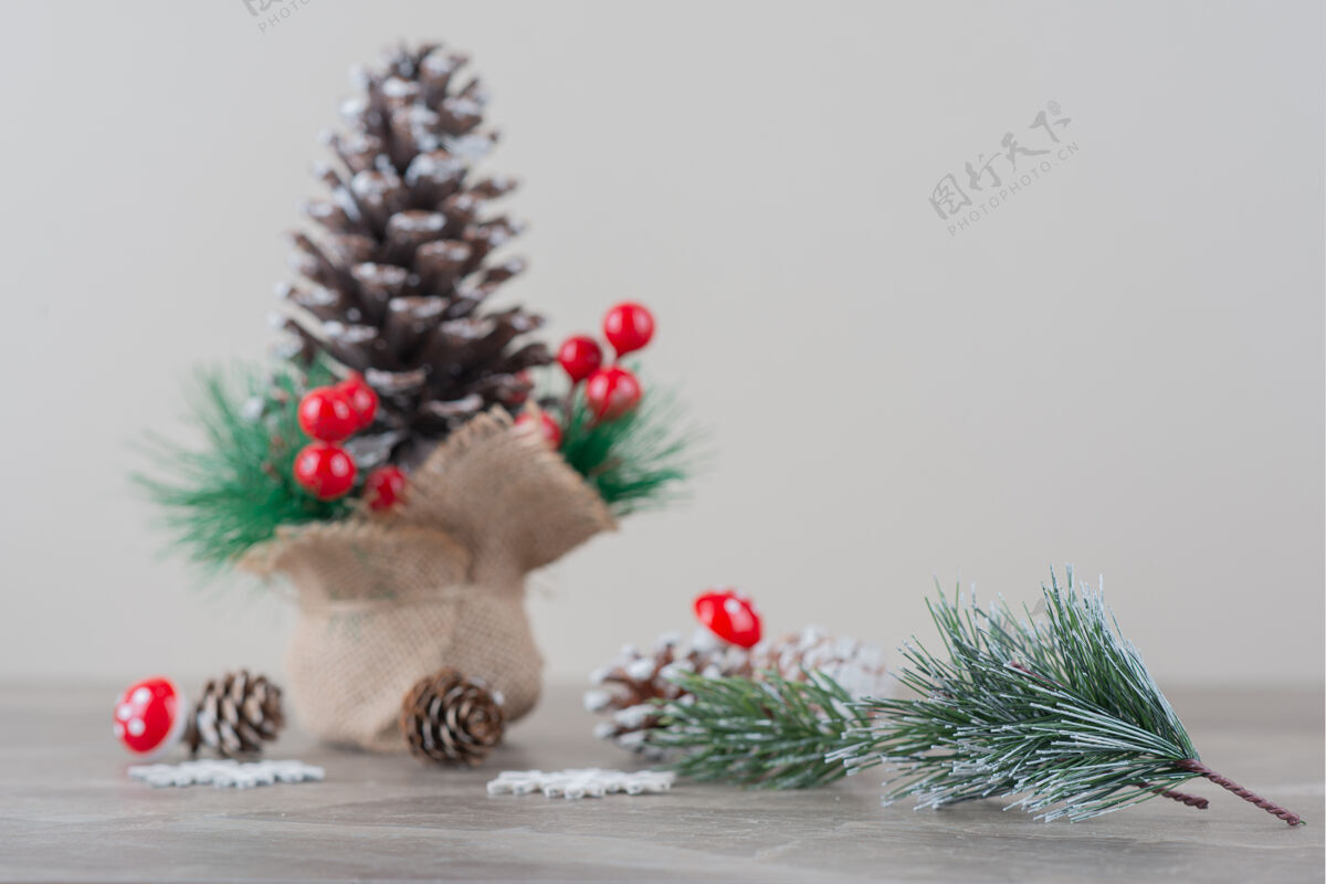 树枝用冬青浆果和树枝装饰的松果放在大理石桌上松树圣诞圆锥形