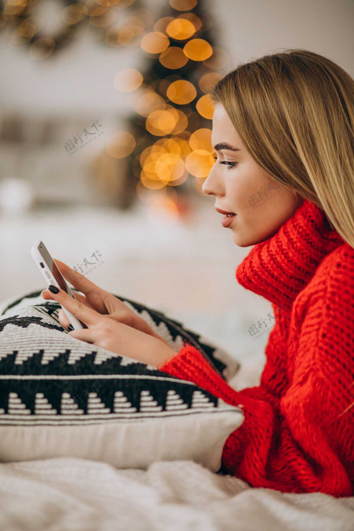 女性在圣诞节用电话的年轻女人快乐互联网灯光
