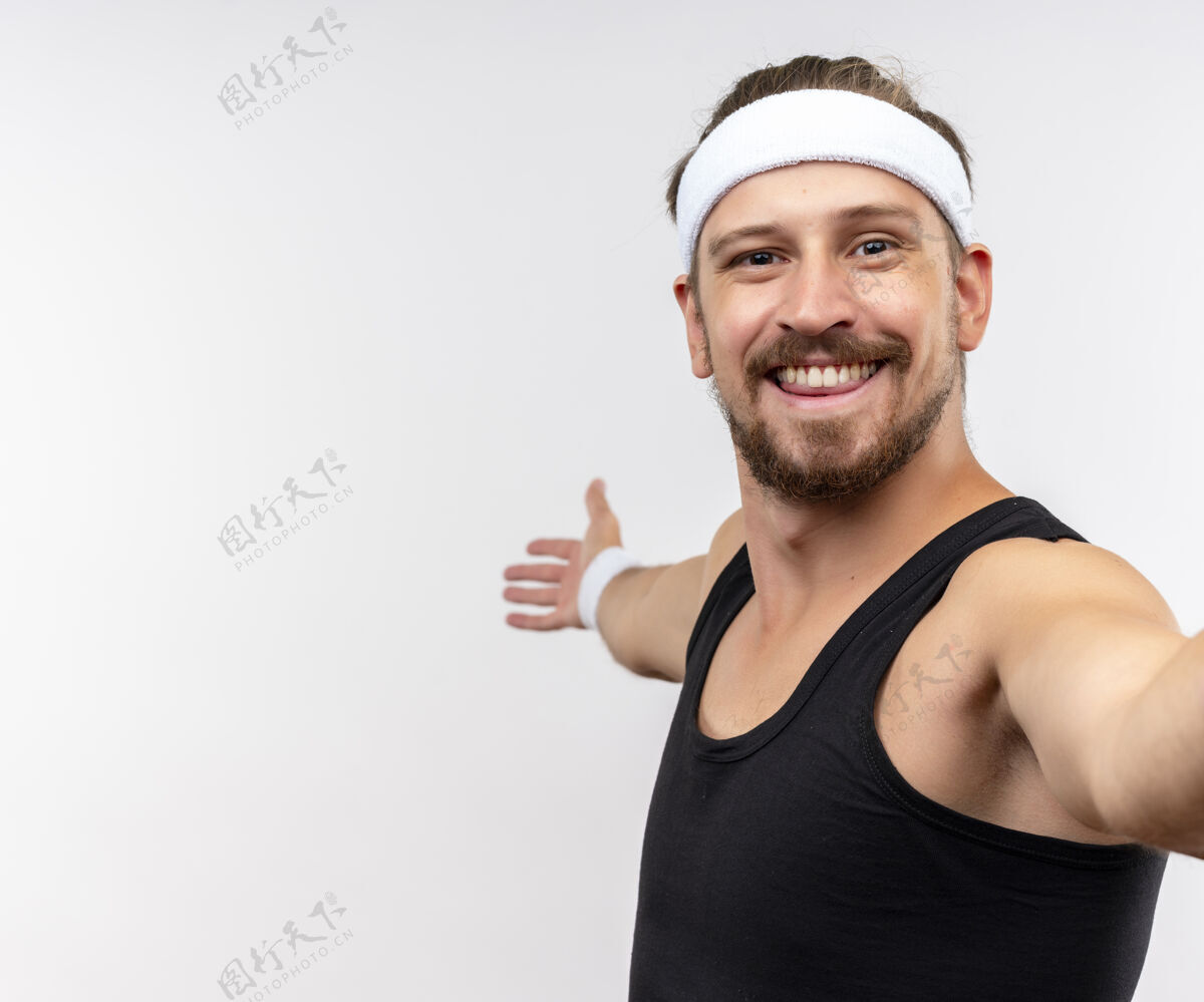 帅气微笑的年轻帅气的运动型男子戴着头带和腕带张开双臂隔离在白色空间头带开放手臂