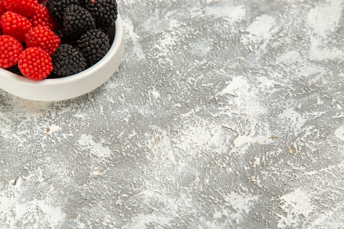 糖顶部近距离观察新鲜浆果 白色表面上有甜甜的糖果糖果甜点黑莓