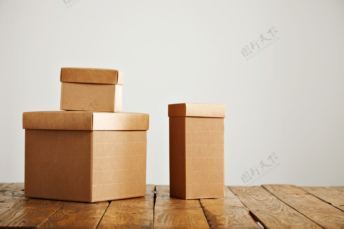 板条箱三个不同大小的米色纸板箱被安排在一个白色墙壁的工作室的棕色乡村桌子上包裹货物磨损